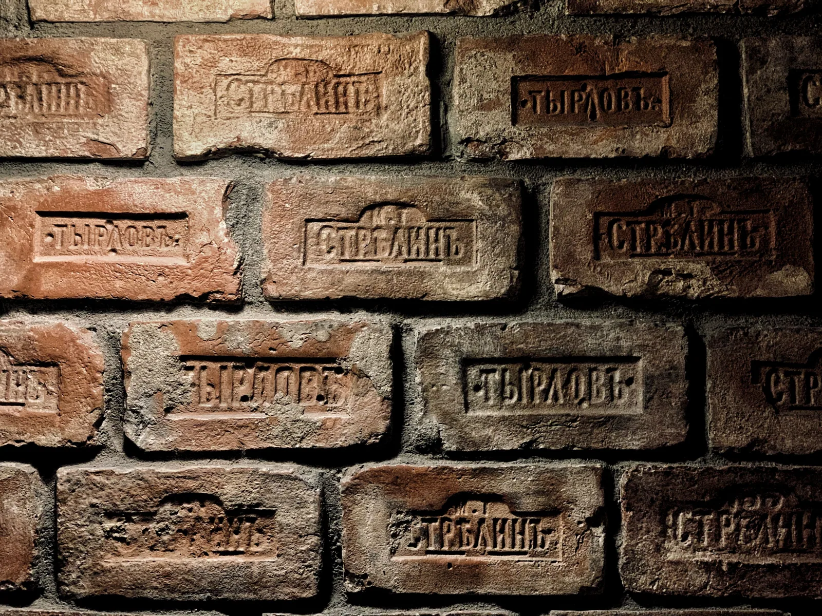 Close-up of aged brick wall with Russian inscriptions, showcasing historical craftsmanship.