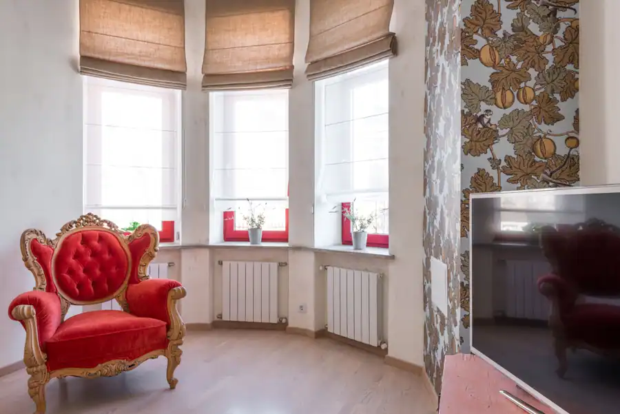 Luxurious red armchair in a stylish room with decorative wallpaper and ample natural light.